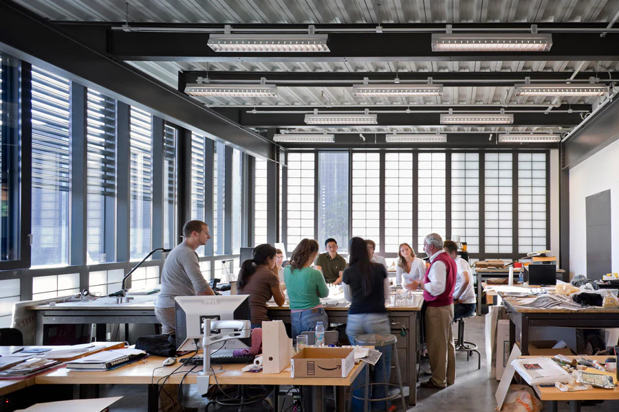 Collaborative workplace with modular suspended lighting system mounted to exposed ceiling for flexible illumination