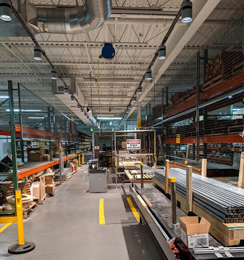 Track busway system providing overhead power and lighting along industrial assembly line in warehouse facility
