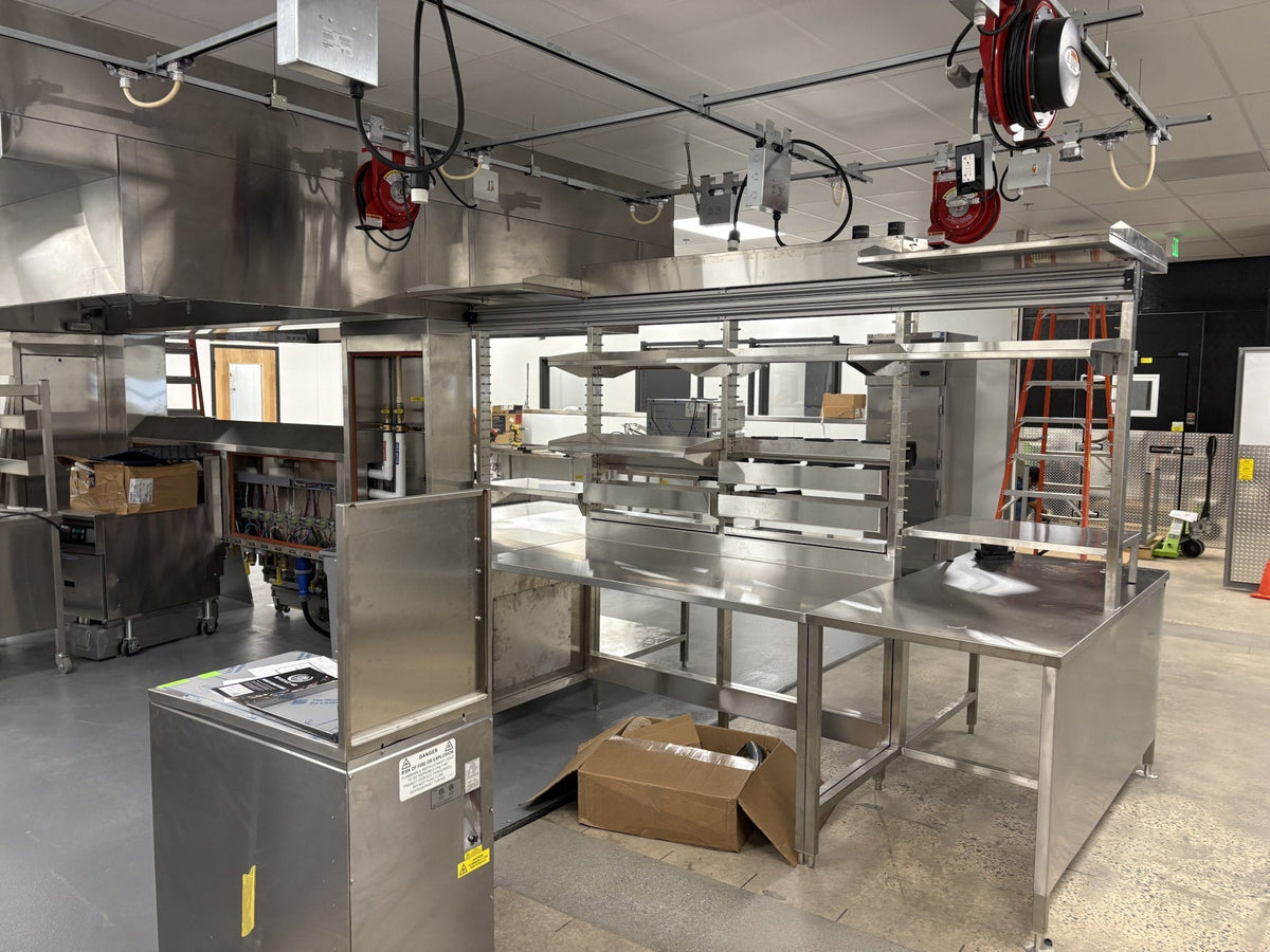 Red retractable cord reels and fixed T40 power drops above stainless-steel equipment during installation