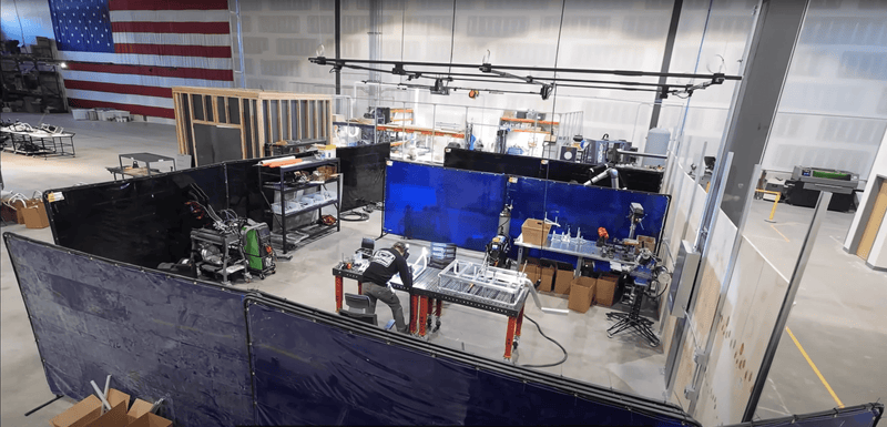 manufacturing facility with track busway suspended overhead for powering welding task