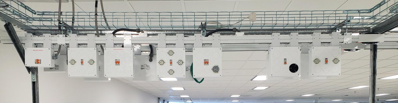 Overhead Track Busway system with multiple plug-in power drops supplying equipment below